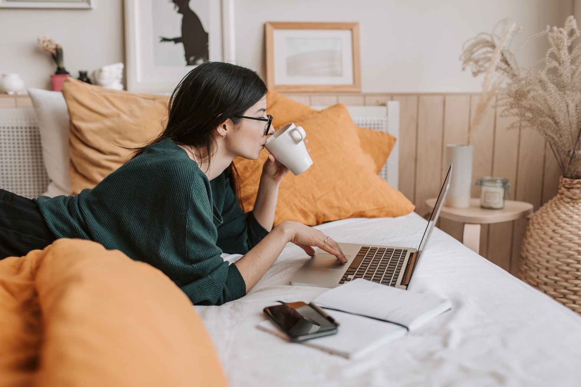 girl laying on bed with laptop and coffee