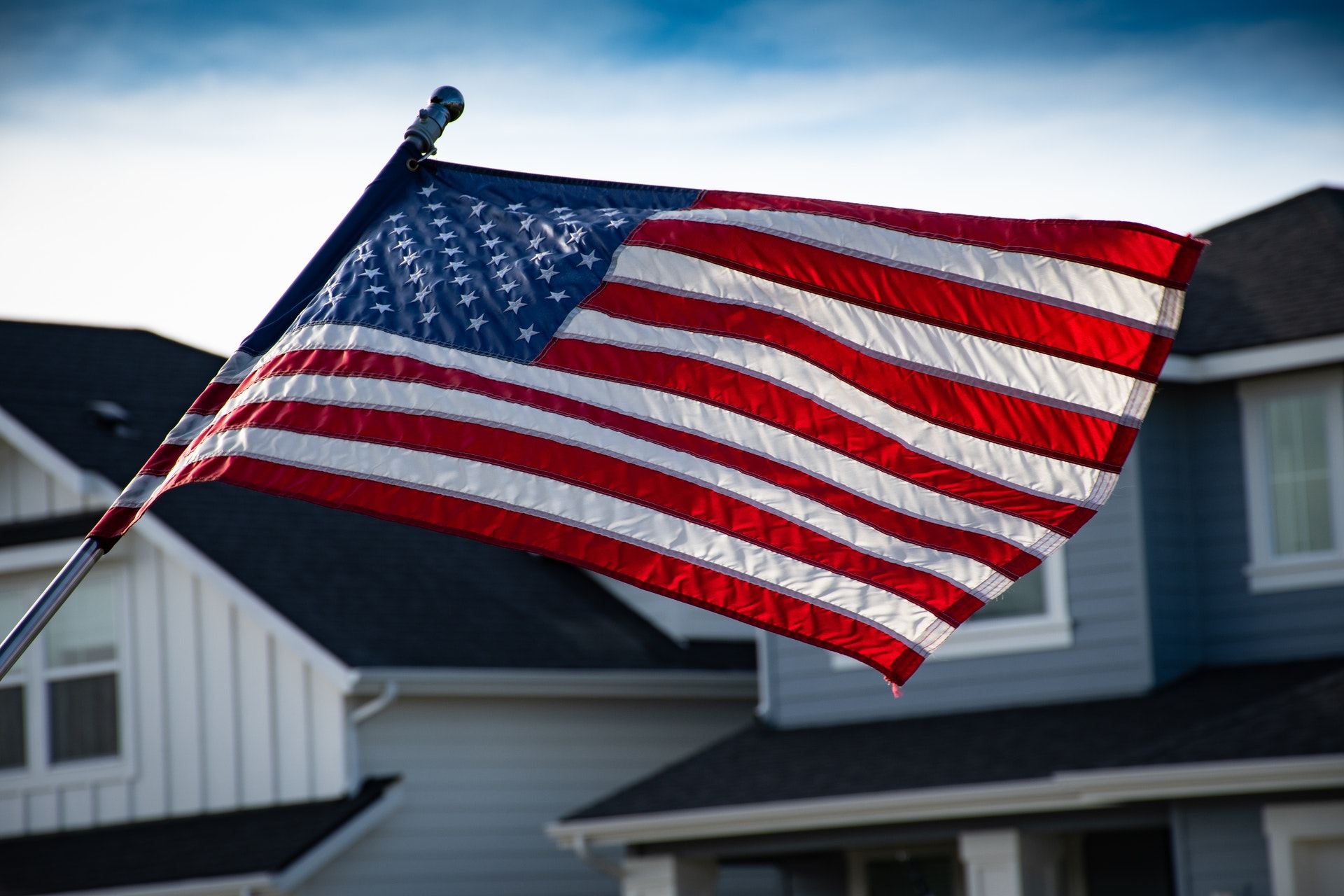 american flag waving by homes
