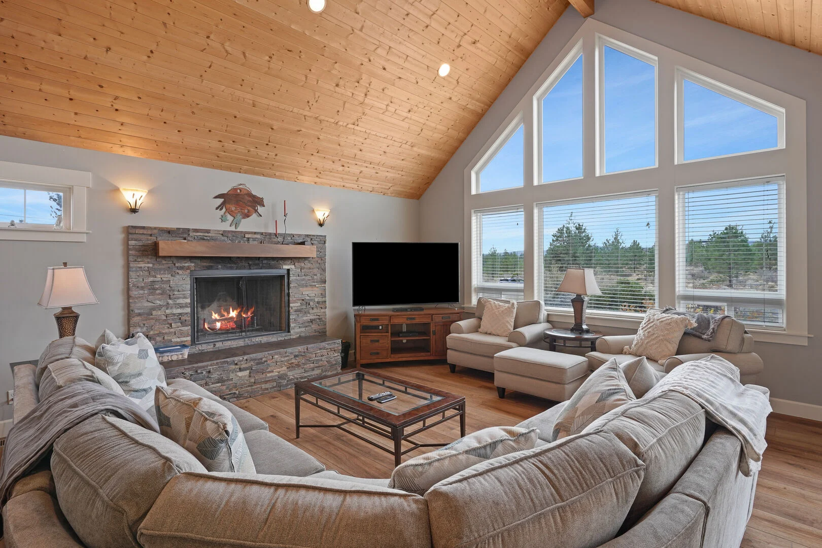 Large living room space with a comfortable couch around a stone fire place in a Arrived Vacation Rental.